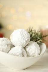 Fototapeta na wymiar Bowl with tasty Christmas snowball cookies on wooden table, closeup