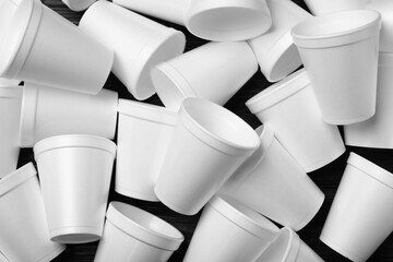 Many white styrofoam cups on black wooden table, flat lay