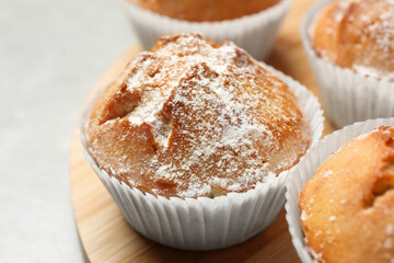 Tasty muffin powdered with sugar on table, closeup