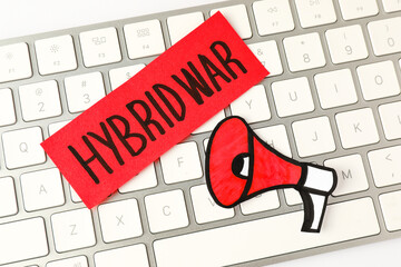 Card with words Hybrid War and paper megaphone on computer keyboard, top view
