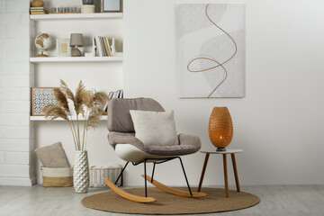 Soft rocking chair with pillow on rug near wall in room. Interior design - obrazy, fototapety, plakaty