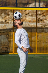 Young male soccer player juggles a ball on a soccer field