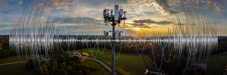 Cell phone tower on sunrise background with a graphic of radio waves superimposed over it.