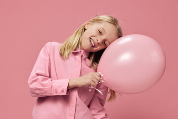 happy, beautiful girl stands with an inflatable pink balloon in her hand and smiles broadly with her eyes closed