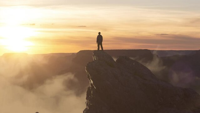 Epic Adventure Composite of Man Hiker on top of a rocky mountain. Dramatic Sunset Sky. 3d Rendering peak. Background landscape from North America. Freedom Concept. Animation