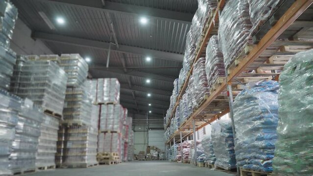 Huge industrial warehouse facility used for cargo supply storage. Storing lots of cargo shipment items at the factory warehouse. Storing the cargo goods on the warehouse shelves. Pallets.