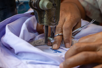 Embroidering Thai numbers on a student's shirt on an old sewing machine