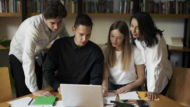 College university students group study together prepare project make notes, happy diverse young people team write essay summary learn in teamwork do creative research homework in library