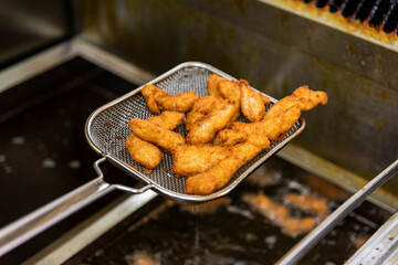 Frying chicken nuggets in deep fryer. Restaurant meal preparation
