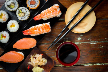 Sushi Set nigiri shrimp and salmon and sushi california rolls with avocado and maki with carrot, on wood,