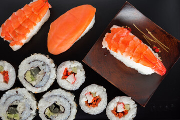 Sushi Set nigiri shrimp and salmon and sushi california rolls with avocado and maki with carrot, on wood,top view