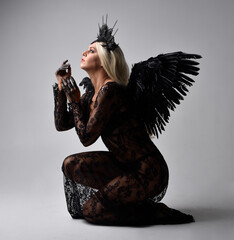portrait of beautiful  model  wearing black gothic dress with headdress  and feathered angel wings....
