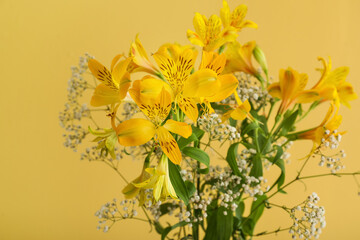 Beautiful alstroemeria and gypsophila flowers near yellow wall, closeup