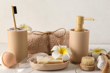 Set of bath supplies with tropical flowers on light background