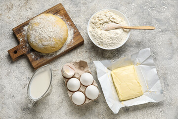 Set of ingredients for baking and raw dough on light background