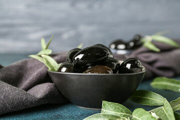 Bowl of tasty black olives on dark table
