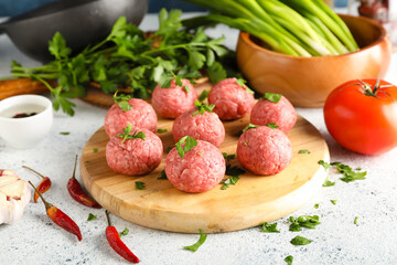 Wooden board with raw meat balls and vegetables on grunge background