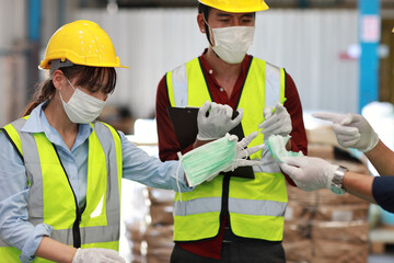 Group of asian technician engineer and businessman in protective uniform inspecting quality of mask and medical face mask production line in factory, manufacturing industry and factory concept.