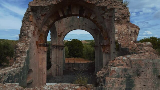 Flying through old Abbazia di San Bruzio, a damaged ruin of an abandoned medieval monastery abbey church in Tuscany of the 11th century surrounded by olive trees in Italy. Cinematic Drone aerial.