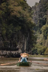 Foto op Canvas Ninh Binh, Vietnam - March 3rd, 2020 : tourist boat on the Ha Long Bay on land in Tam Coc, Vietnam with karst mountains in the background © LeaGuPhoto