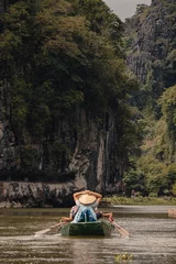 Foto op Canvas Ninh Binh, Vietnam - March 3rd, 2020 : tourist boat on the Ha Long Bay on land in Tam Coc, Vietnam with karst mountains in the background © LeaGuPhoto