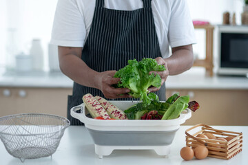 Male senior hands washing vegetables for making fresh salads in the kitchen, Healthy food