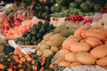 A fruit stall at the morning market in Hoi An, Vietnam with mangoes and tangerines