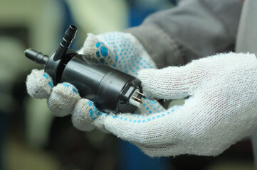 Spare parts for a passenger car. Car headlight washer pump. Close-up. An auto mechanic inspects the...