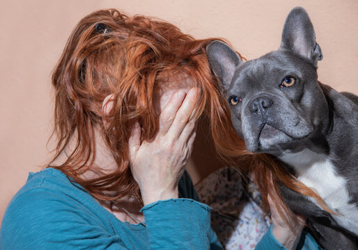 Eine Frau und ihr Hund sitzen traurig eng zusammen