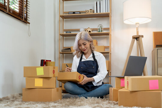 Asian woman entrepreneurs wokring at home with many parcel bxes, Small business Startup Ideas. SME or freelance business online and delivery concept.