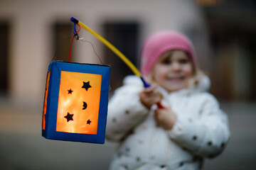 Close-up of little kid girl holding selfmade lanterns with candle for St. Martin procession....