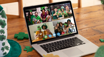 Diverse friends in costumes making st patrick's day video call displayed on laptop screen at home