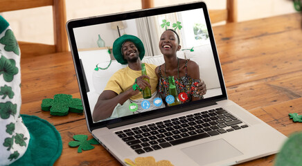 African american couple having st patrick's day video call smiling on laptop screen at home