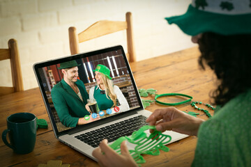 Mixed race woman making st patrick's day video call to smiling couple in costumes on laptop at home - Powered by Adobe