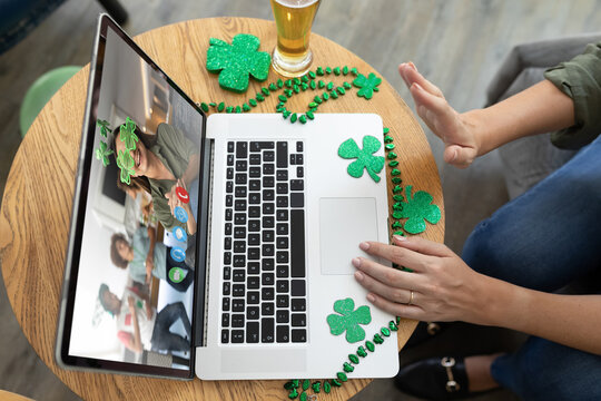Caucasian woman at bar making st patrick's day video call waving to friends in costume on laptop