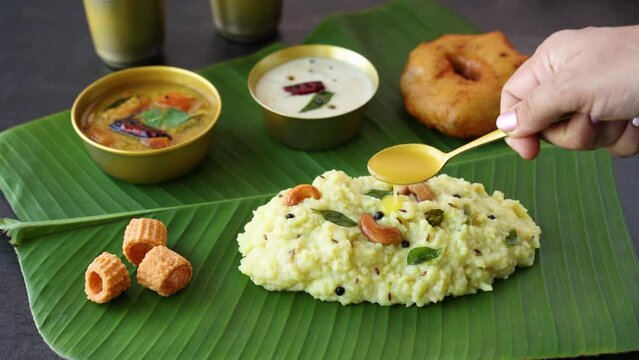 Ven Pongal Khara Pongal Sambar coconut chutney woman hand serving Indian breakfast food Tamil Nadu festival Pongal Sankranti Diwali spicy pongal using rice lentil semolina rava South India Sri Lanka