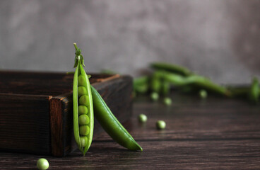 fresh pea pod open with peas on a wooden background