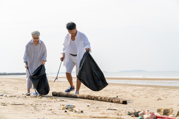 Asian family senior couple on summer holiday vacation. Retired elderly man and woman picking up plastic bottle and garbage on the beach. Environment protection volunteer and waste pollution concept