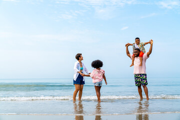 African family on beach holiday vacation. Father and mother with little daughter and son playing together on the beach at summer sunset. Parents with kid enjoy outdoor lifestyle together at the sea