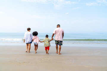 African family on beach holiday vacation. Father and mother with little daughter and son playing together on the beach at summer sunset. Parents with kid enjoy outdoor lifestyle together at the sea