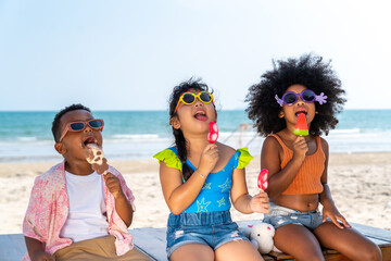 Group of Diversity little boy and girl kid eating ice cream while playing together on the beach in...