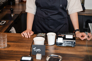 Fototapeta na wymiar Shot of woman coffee maker with apron inside counter of coffee shop.