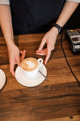Shot of elderly woman barista with capuccino in counter of modern coffee shop.