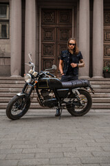 Fototapeta na wymiar Shot of brutal motorcyclist with beard and long hairs driving motorbike.
