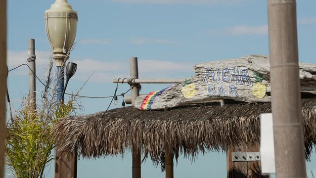 This video shows an aloha bar with it's straw roof blowing in the wind.
