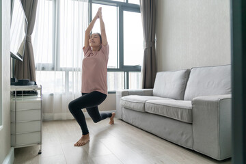  Young Asian woman in sportswear learning workout exercise by watching exercise tutorials online class on laptop computer in living room at home. Home fitness for good shape and health care concept.