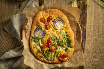 Garden art focaccia bread with vegetables, greens, herbs - beautiful flower composition on homemade...