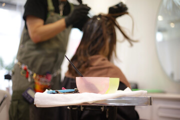 Obraz na płótnie Canvas 女性の髪に薬剤を塗布する男性美容師