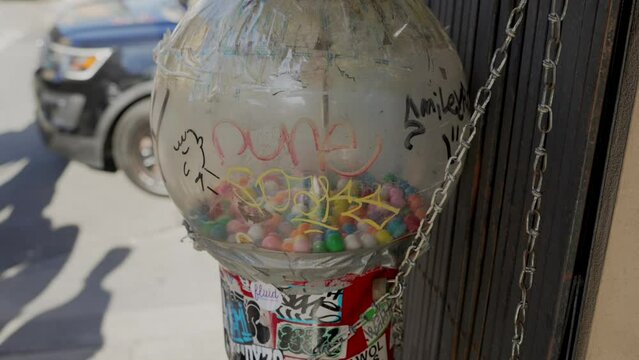 This video shows a dirty old gum ball machine covered with graffiti.