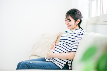 部屋のソファに座る妊婦（マタニティ・妊娠・赤ちゃん）

